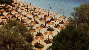 Una playa con numerosas sombrillas y gente descansando en la arena.