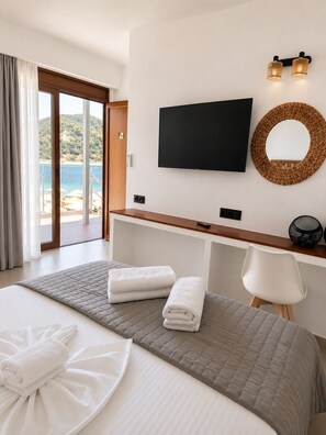 A hotel room with a bed, a TV, a desk, and a view of the sea. - Blue Green Bay (Skopelos)