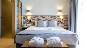 Una habitación de hotel con una cama grande, dos mesitas de noche, un cabecero de madera y dos luces fijadas a la pared.