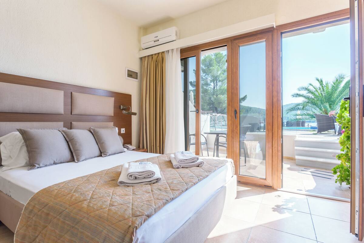A hotel room with a large bed, a view of the outdoors, and a sliding glass door.