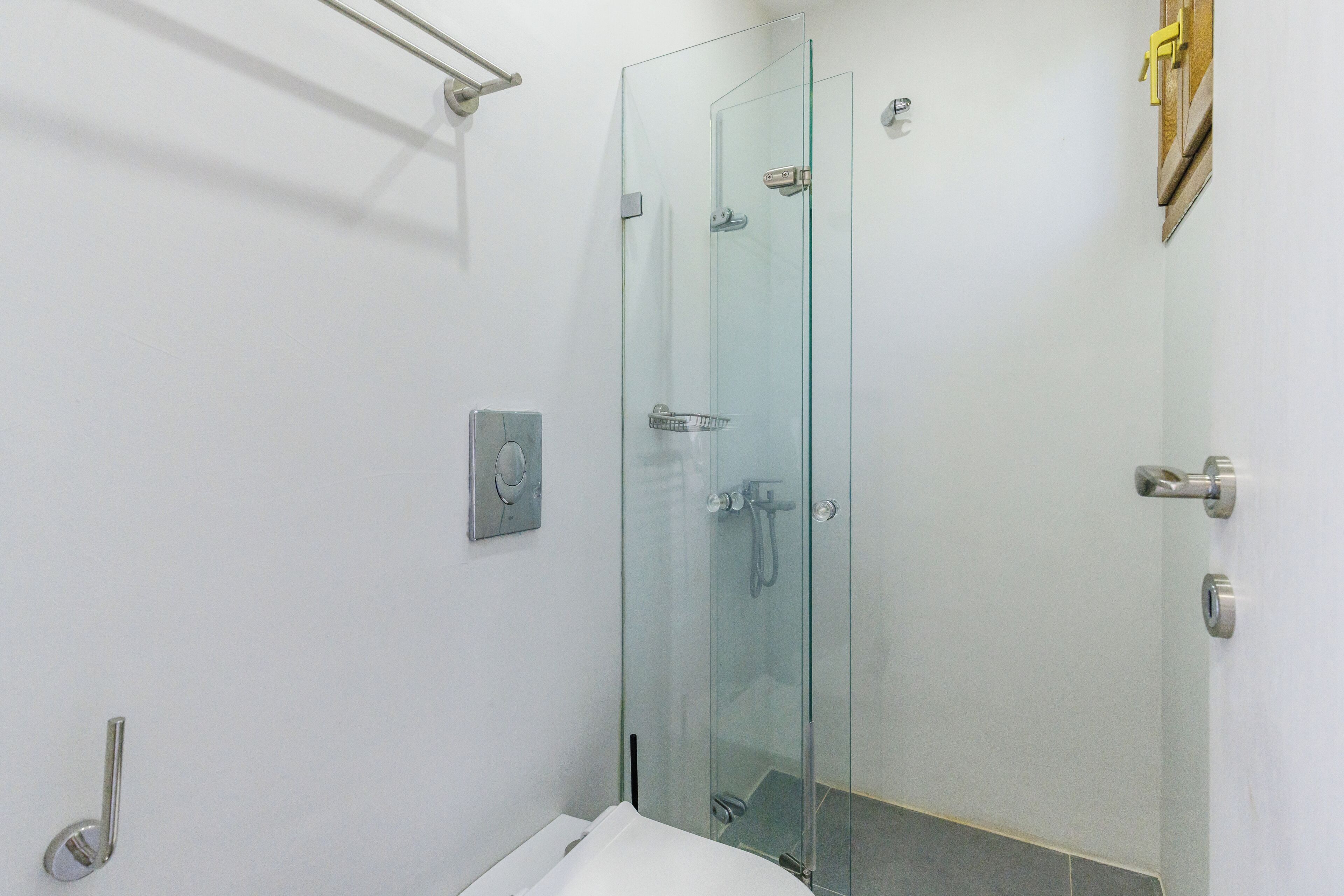 Un baño moderno con cabina de ducha de vidrio, inodoro y barra para toallas.