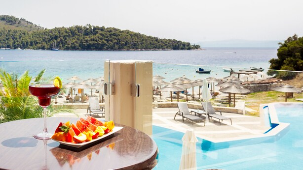 Vista de la piscina con una mesa, un plato de fruta y una bebida.