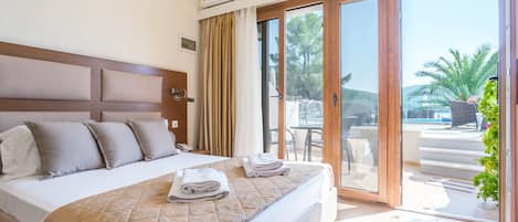 A hotel room with a large bed, a view of the outdoors, and a sliding glass door.