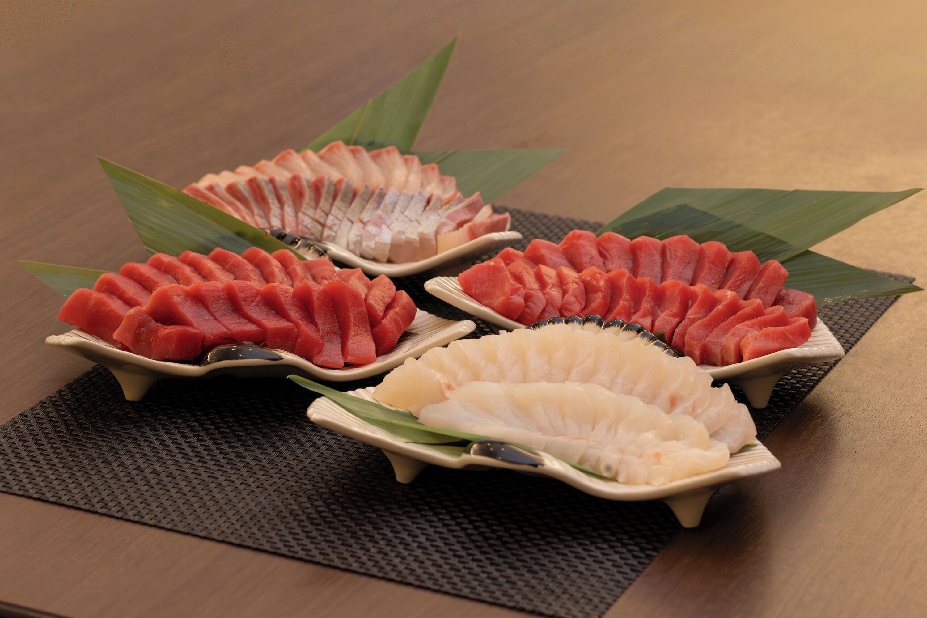 Tres porciones de sashimi sobre una mesa con posavasos.