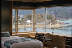 A bedroom with a large window, a bed, a desk, and a chair. - Fuji Lake Hotel (Fujikawaguchiko)