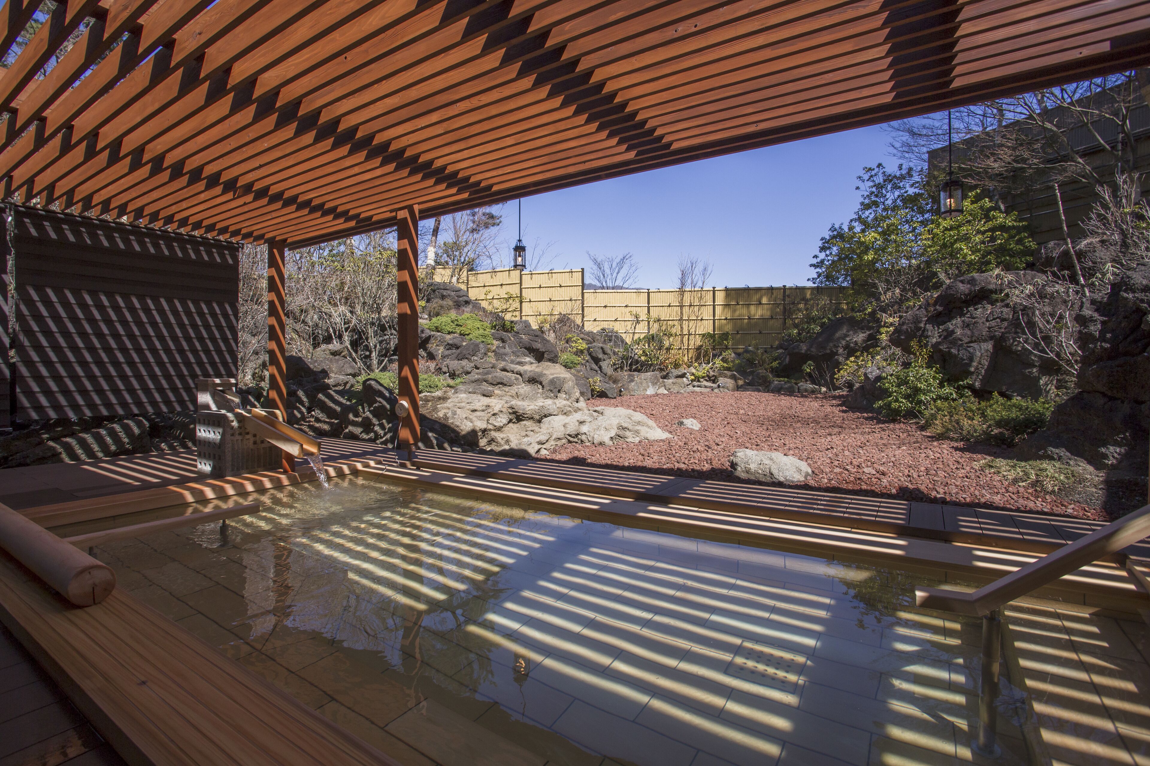 A traditional Japanese onsen with wooden flooring and a wooden roof structure.