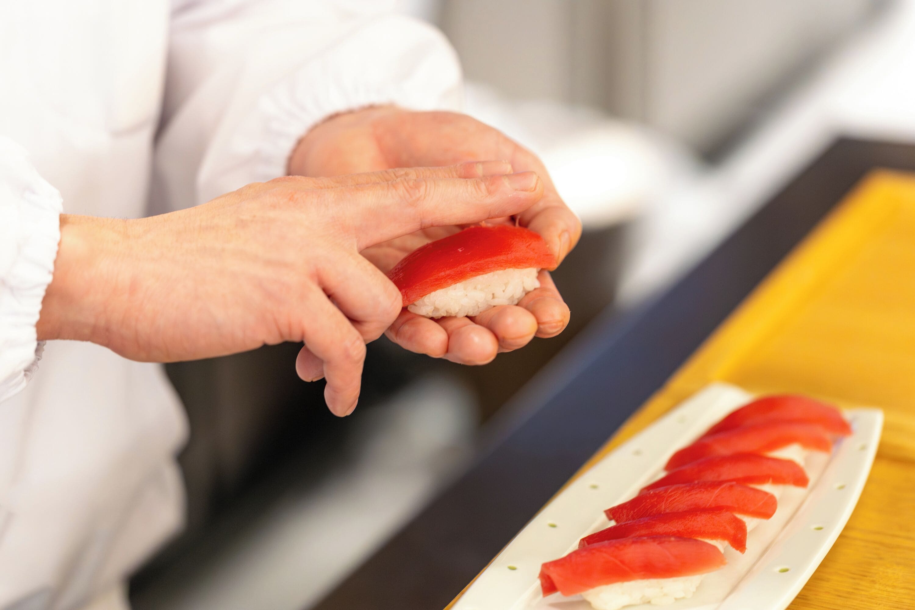 A person holding a sushi roll.