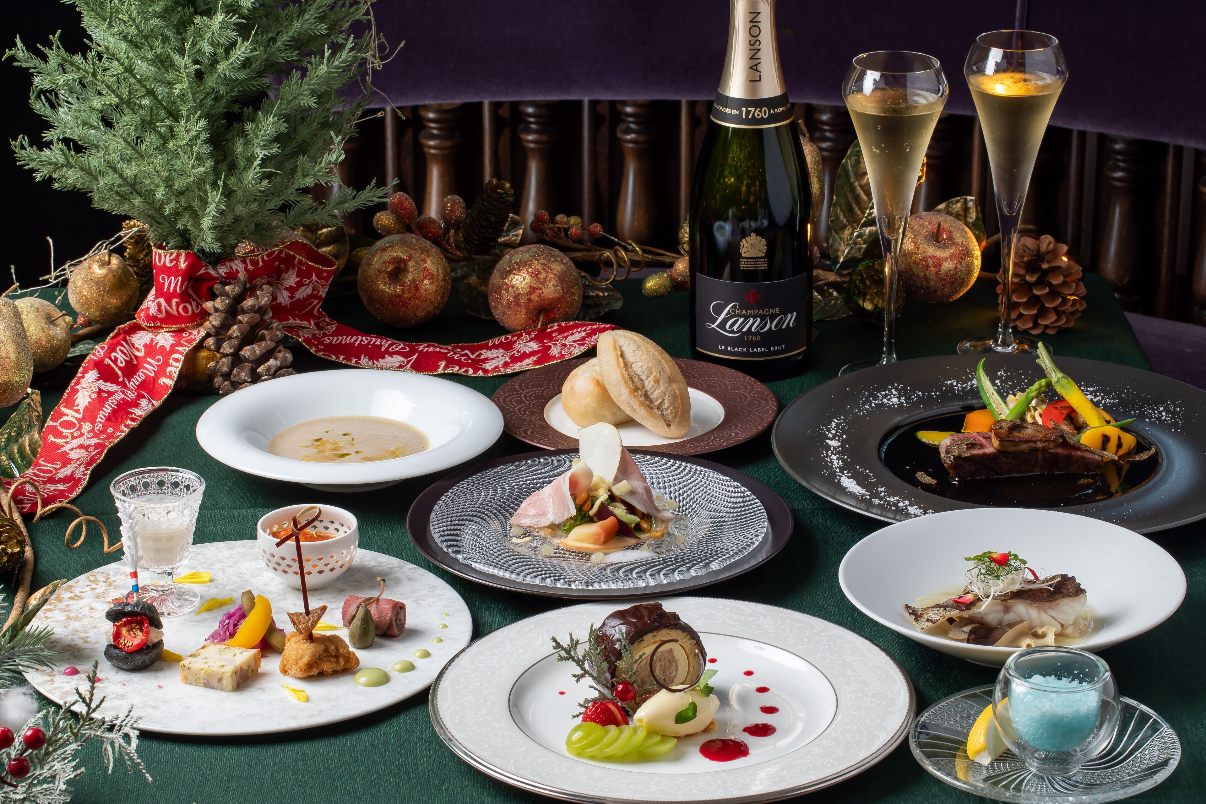 A table set with various dishes, a bottle of champagne, and Christmas decorations.