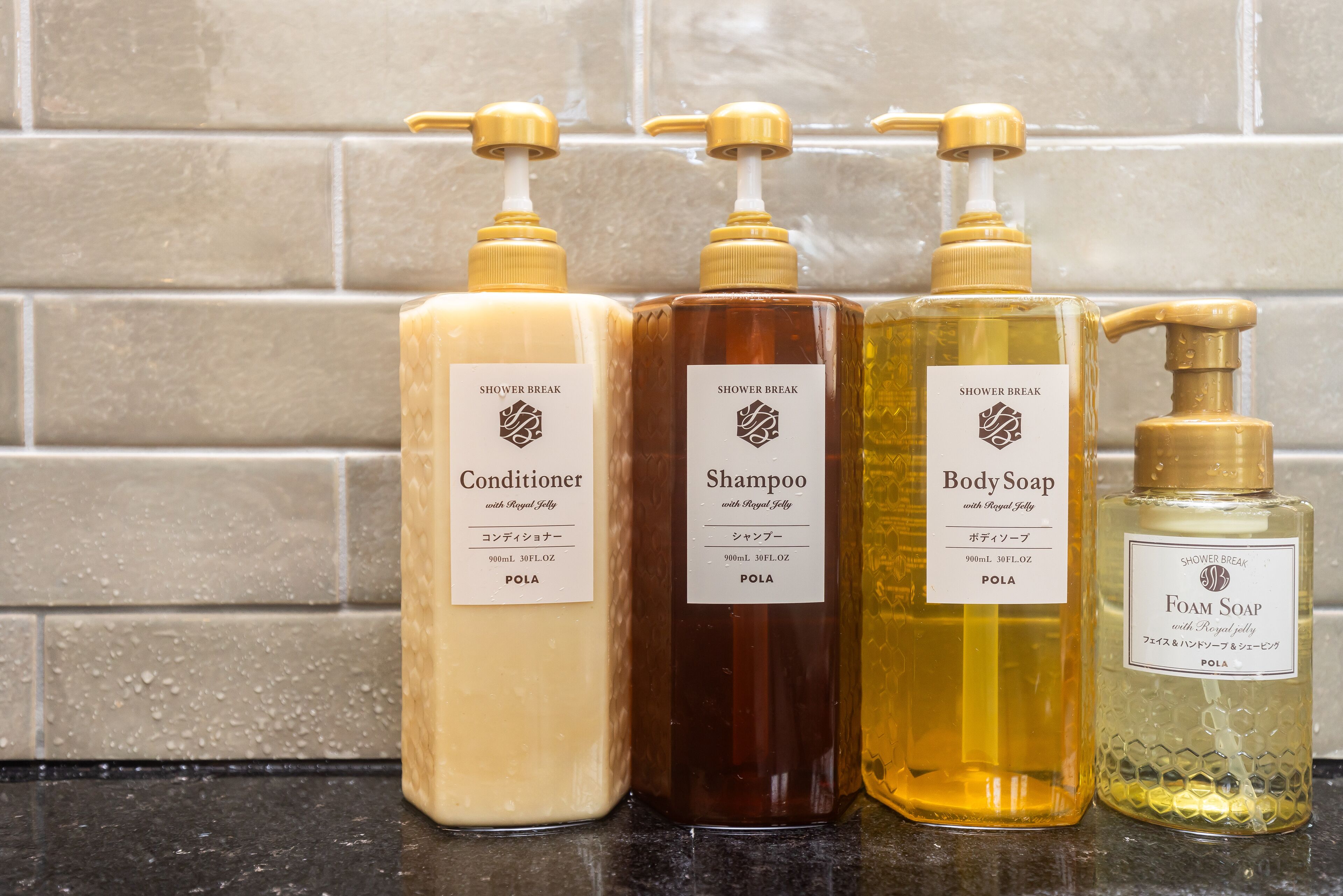 Quatre flacons de produits pour la douche sont posés sur un comptoir.