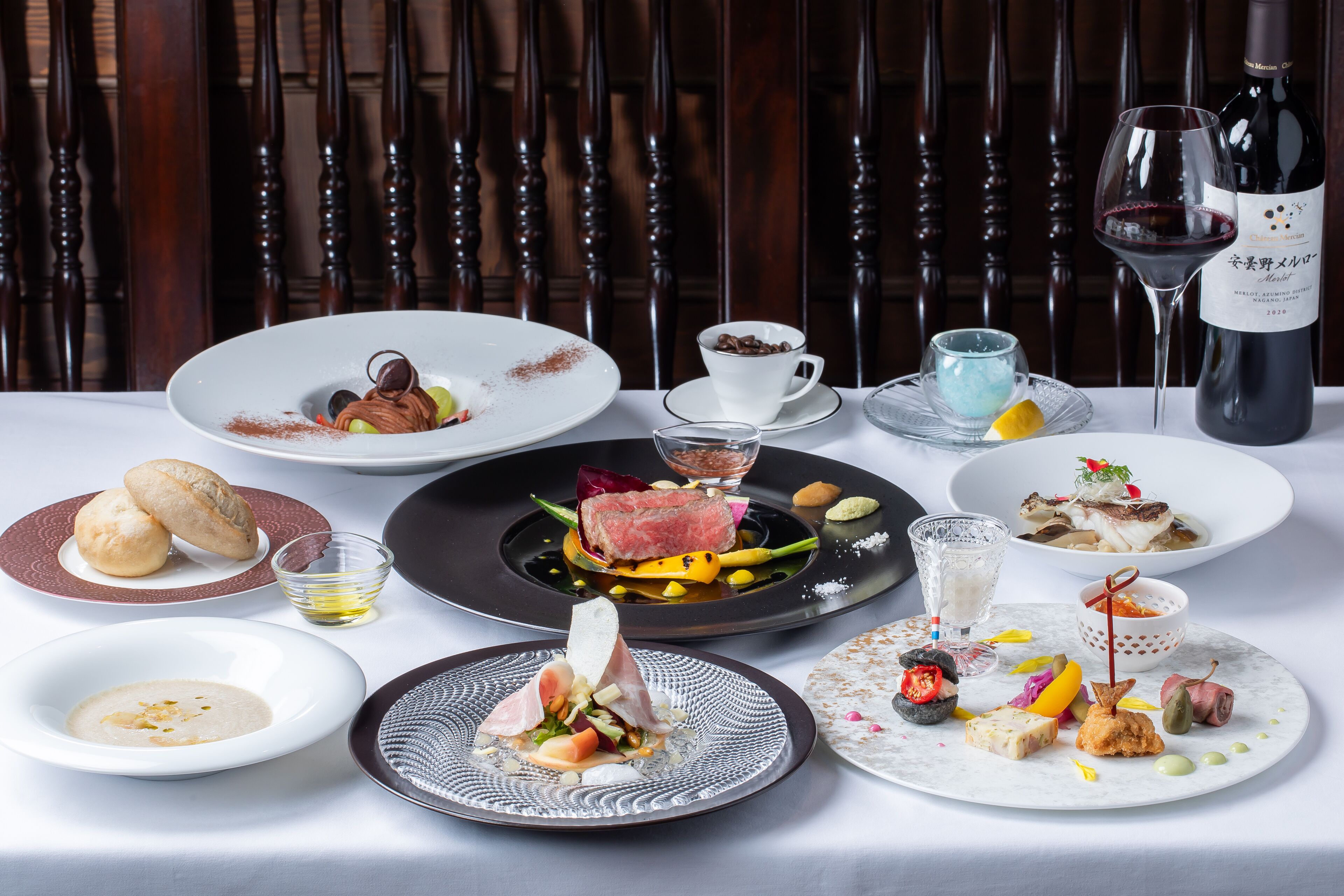 A table set with various dishes and a bottle of wine, suggesting a fine dining experience.