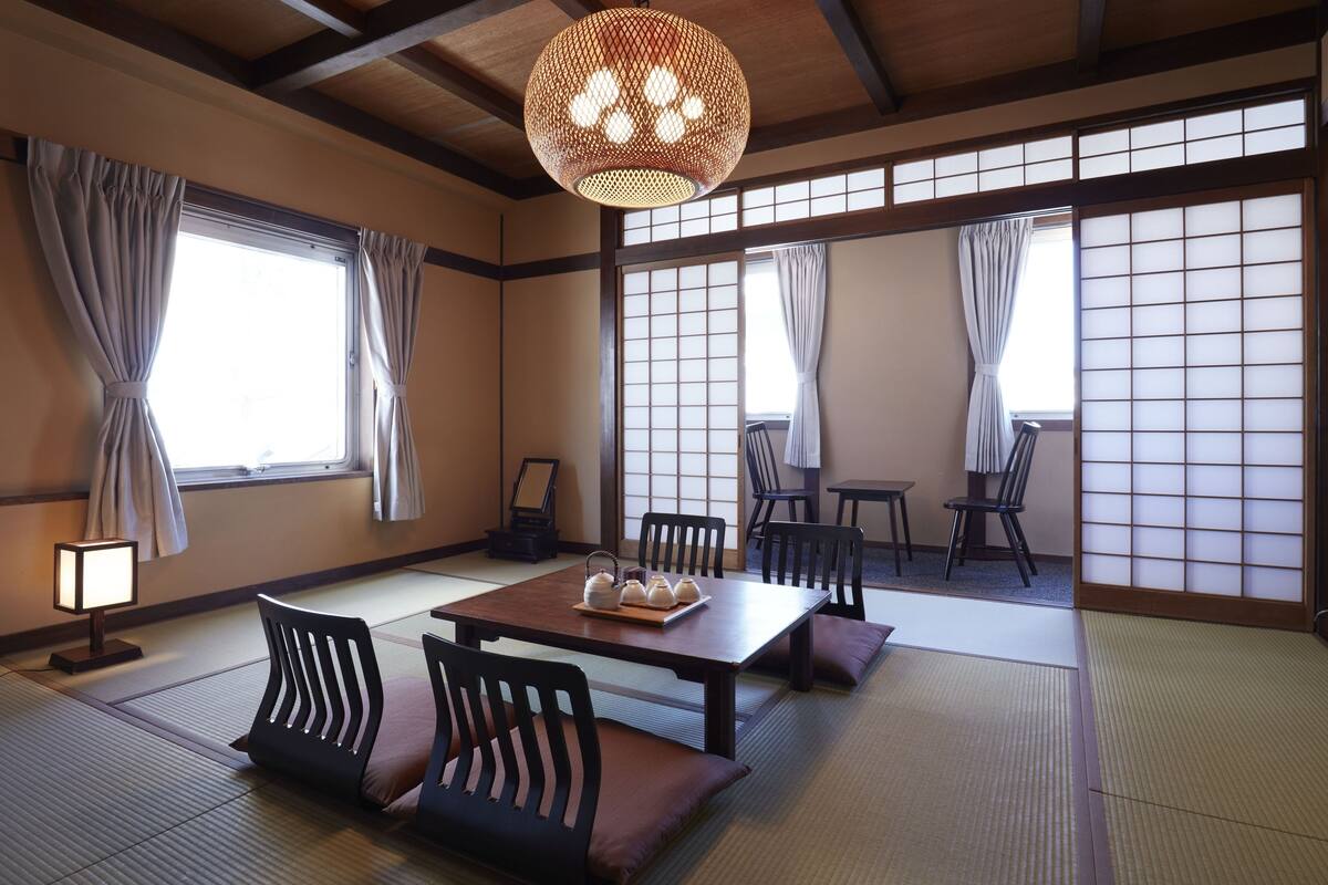 A traditional Japanese room with tatami flooring, a low table with cushions, and sliding shoji doors.