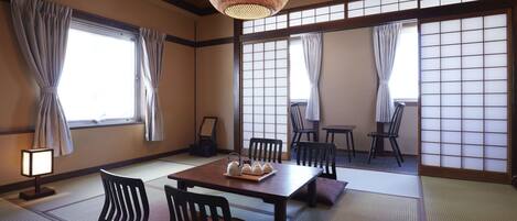 A traditional Japanese room with tatami flooring, a low table with cushions, and sliding shoji doors.