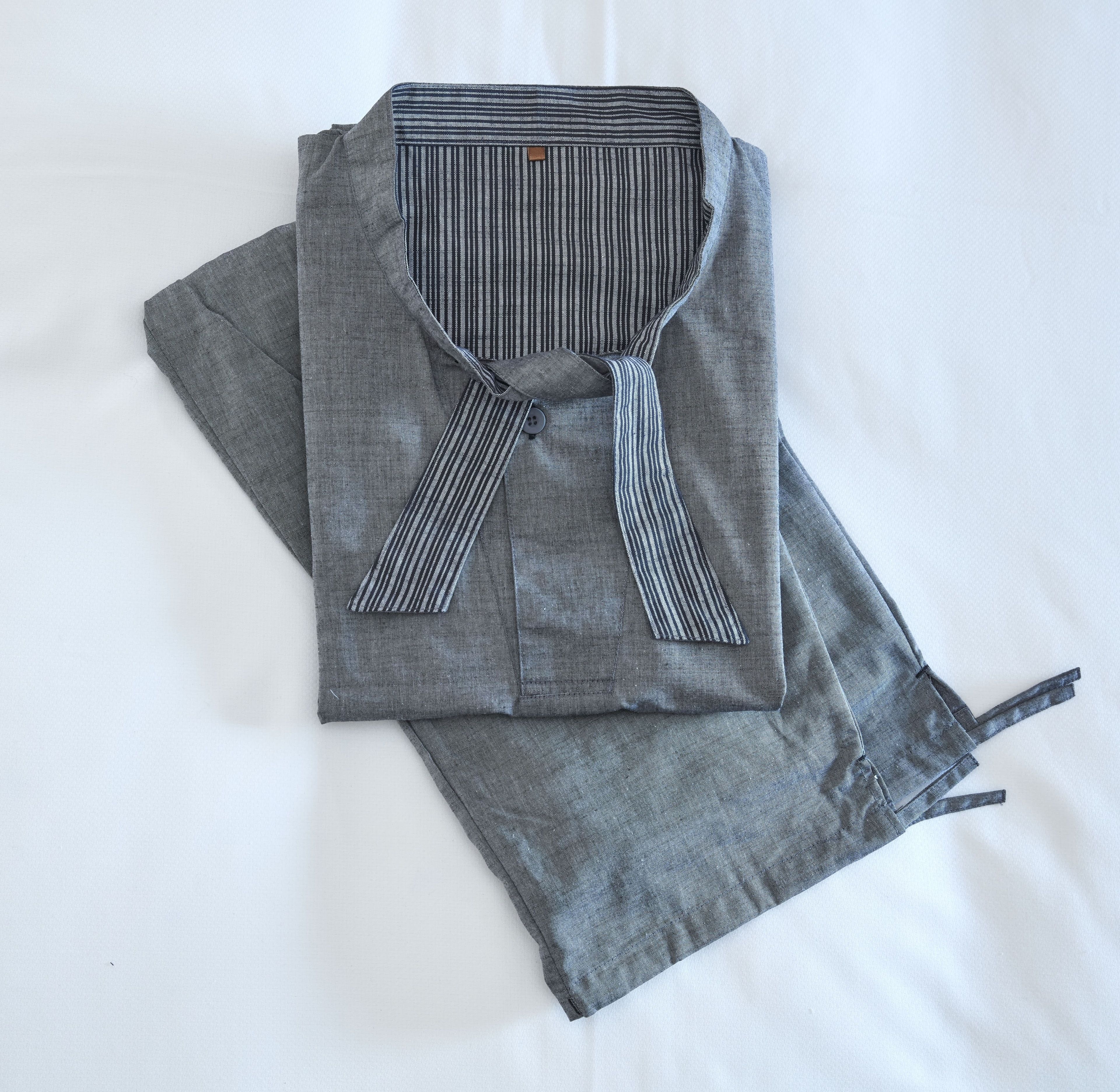 A neatly folded grey shirt with a striped collar and a button-down front.