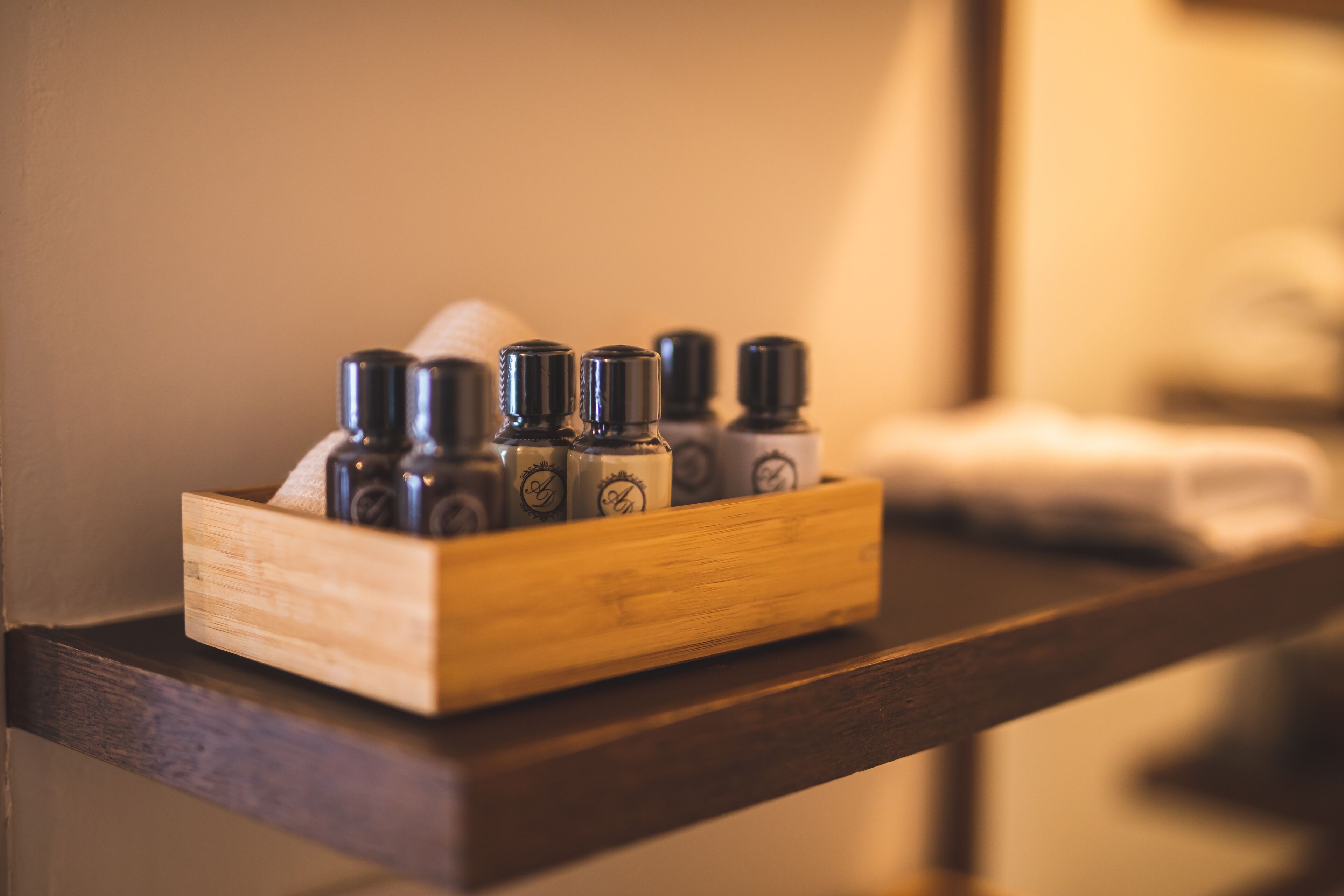 A wooden tray holding several bottles of essential oils on a wooden shelf.
