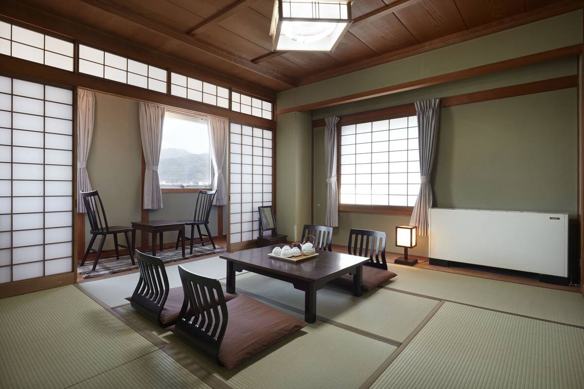 A traditional Japanese room with tatami flooring, a low table with cushions, and sliding doors.