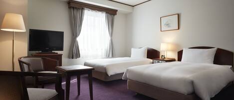 A hotel room with two beds, a TV, a desk, and a chair.