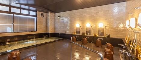 A spacious indoor pool area with a tiled floor, a wooden ceiling, and a glass partition.