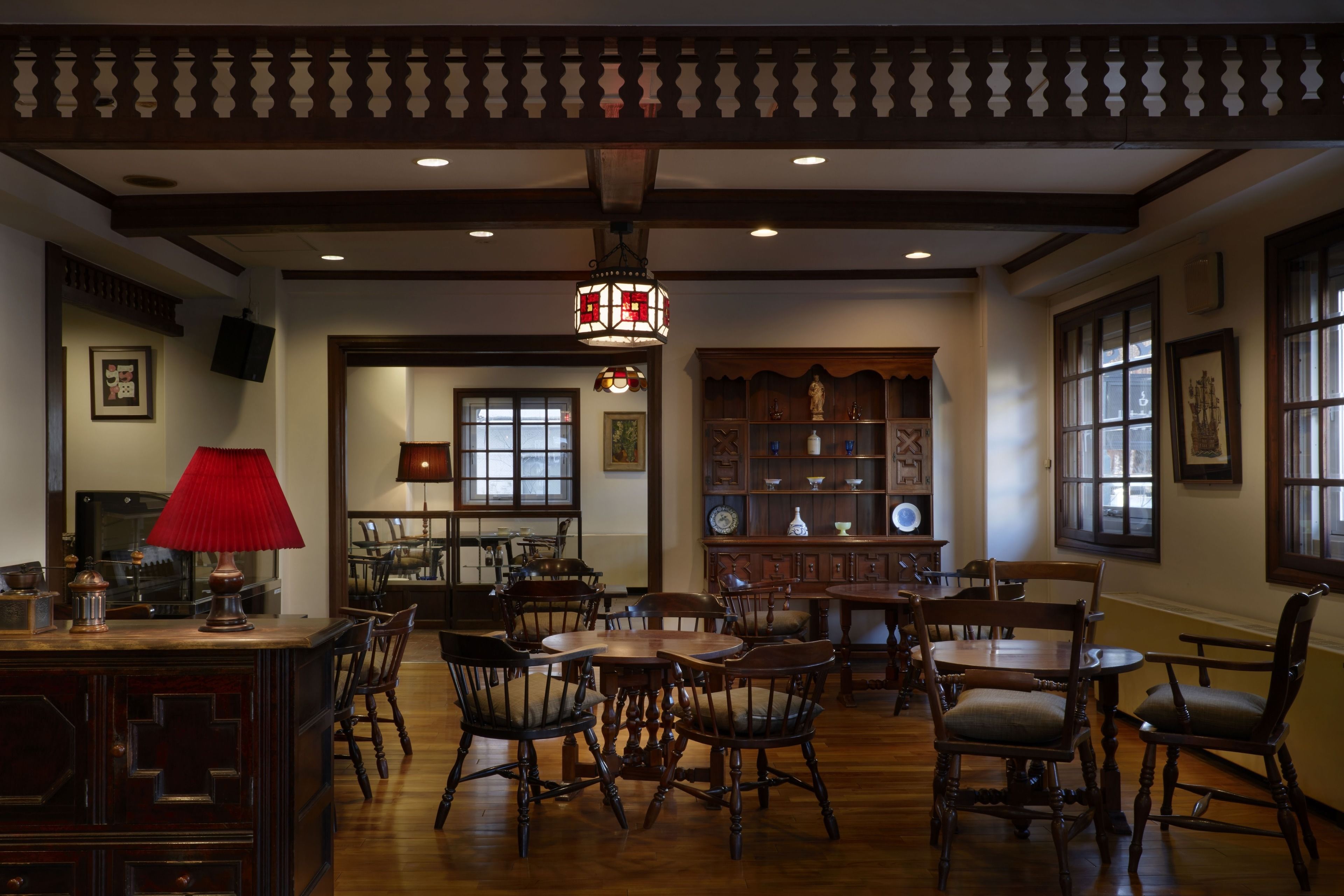 Un comedor tradicional con muebles de madera, una lámpara de mesa roja y una lámpara de techo decorativa.