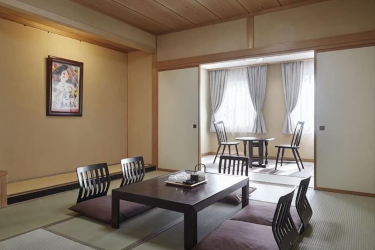 A traditional Japanese room with tatami flooring, a low table, chairs, and a sliding door.