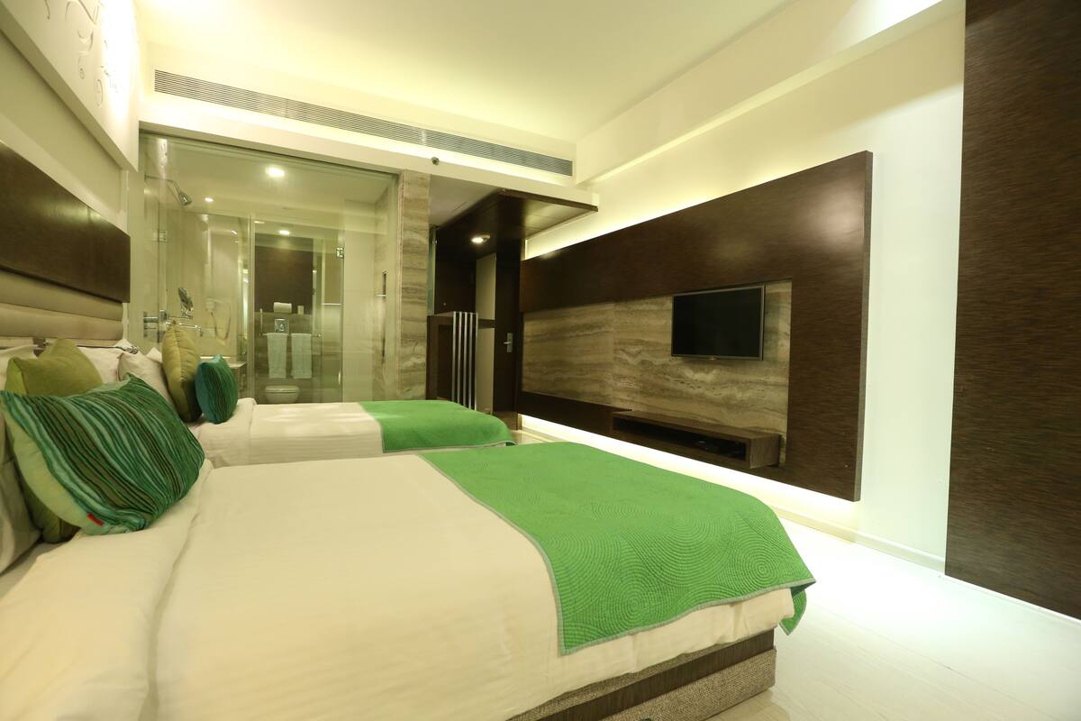 Ein modernes Schlafzimmer mit einem großen Bett, einem an der Wand montierten Fernseher und einer Duschkabine aus Glas.