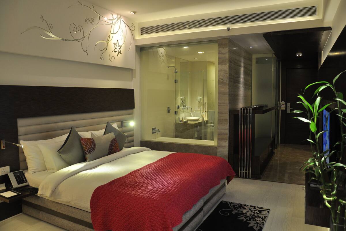 Ein modernes Hotelzimmer mit einem großen Bett, einer Glaskabine für die Dusche und Blick auf die Stadt.