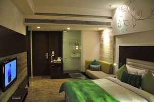 Una habitación de hotel con cama, televisión, sofá y una mesita.