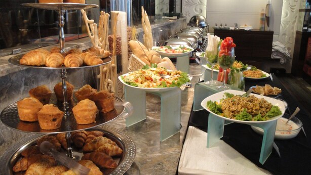 A buffet with various food items including pastries, salads, and a variety of dishes. - Maya Hotel (Chandigarh)