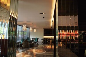A modern interior with a dining area, seating, and a bar with illuminated shelves. - Maya Hotel (Chandigarh)
