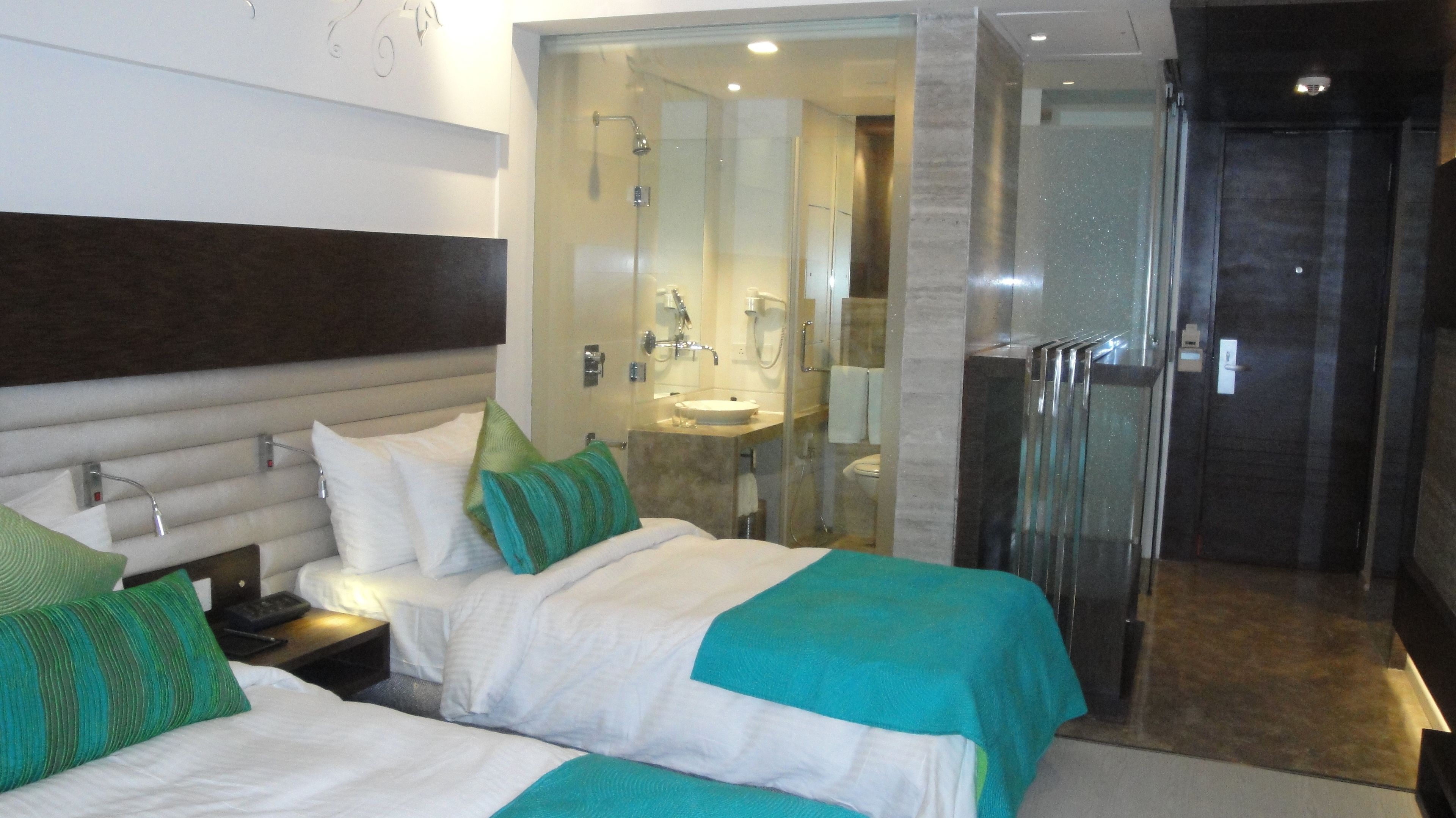 A hotel room with two beds, a bathroom, and a shower area.
