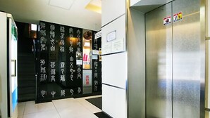 A hallway with a metallic elevator and a wall with vertical text. - HIT Hotel (Seoul)
