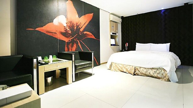 A modern hotel room with a large bed, a desk with a chair, a small table, and a large wall mural. - HIT Hotel (Seoul)