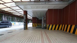 A covered pedestrian walkway with tiled flooring and striped safety barriers. - HIT Hotel (Seoul)