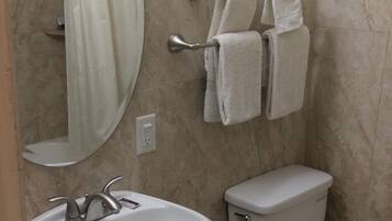 A bathroom with a pedestal sink, a toilet, and a towel rack with towels.