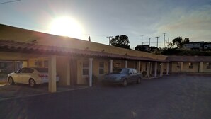 A motel with a row of rooms, each with a covered parking area. - El Rey Motel (Globe)