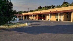 A motel with a large parking lot and a red vehicle parked inside. - El Rey Motel (Globe)