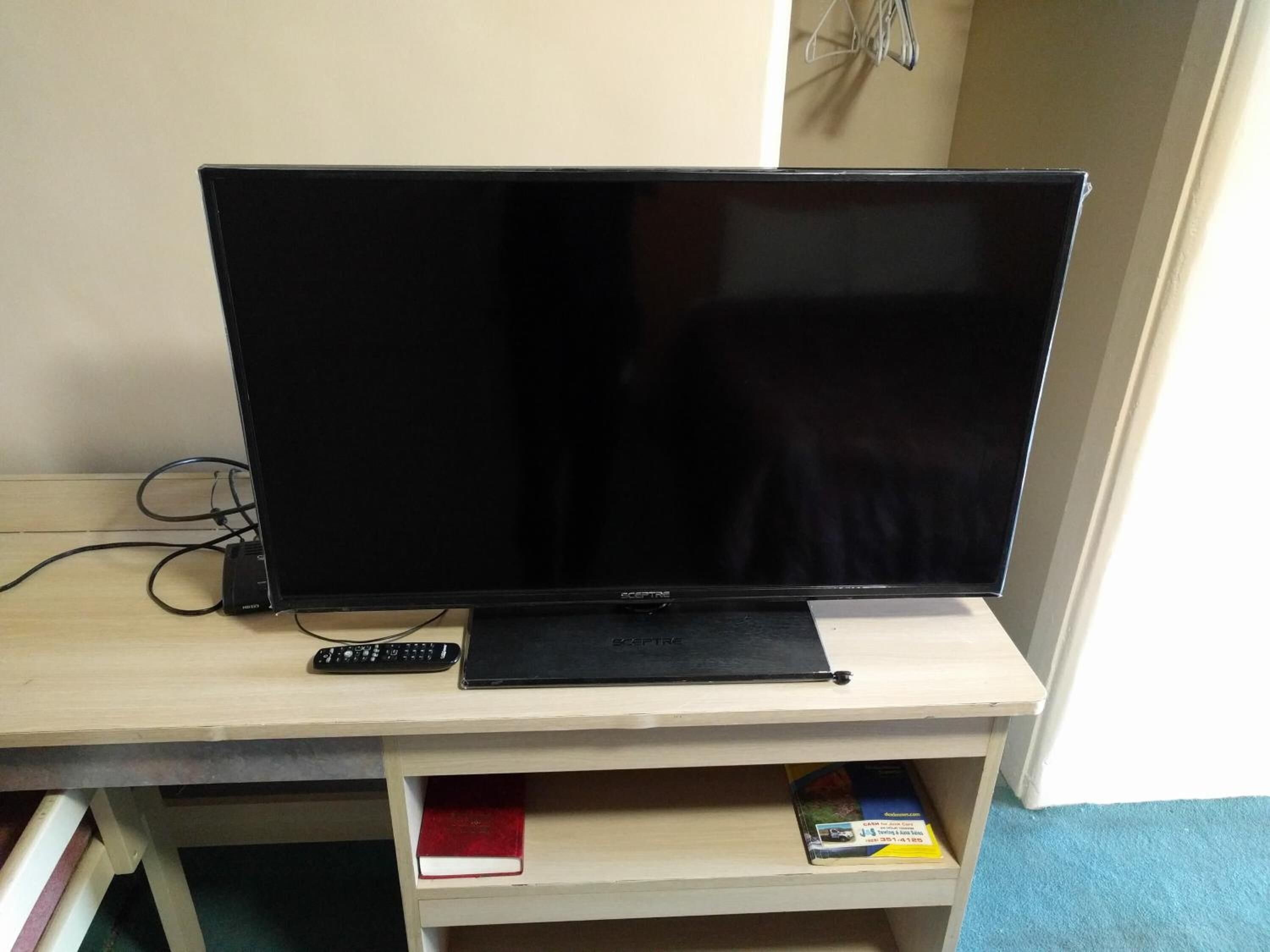 Ein Flachbildfernseher auf einem Holz-TV-Möbel mit Fernbedienung.