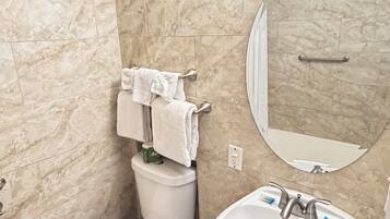 A bathroom with a toilet, sink, and mirror.