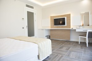 A hotel room with a bed, a desk, a chair, a TV, and a mirror. - Selcukhan Hotel (Kemer)