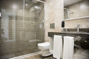 A modern bathroom with a glass-enclosed shower, a toilet, and a vanity with a mirror and towel rack. - Selcukhan Hotel (Kemer)