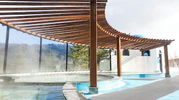 Un área de spa con una pérgola de madera, un jacuzzi y una piscina.