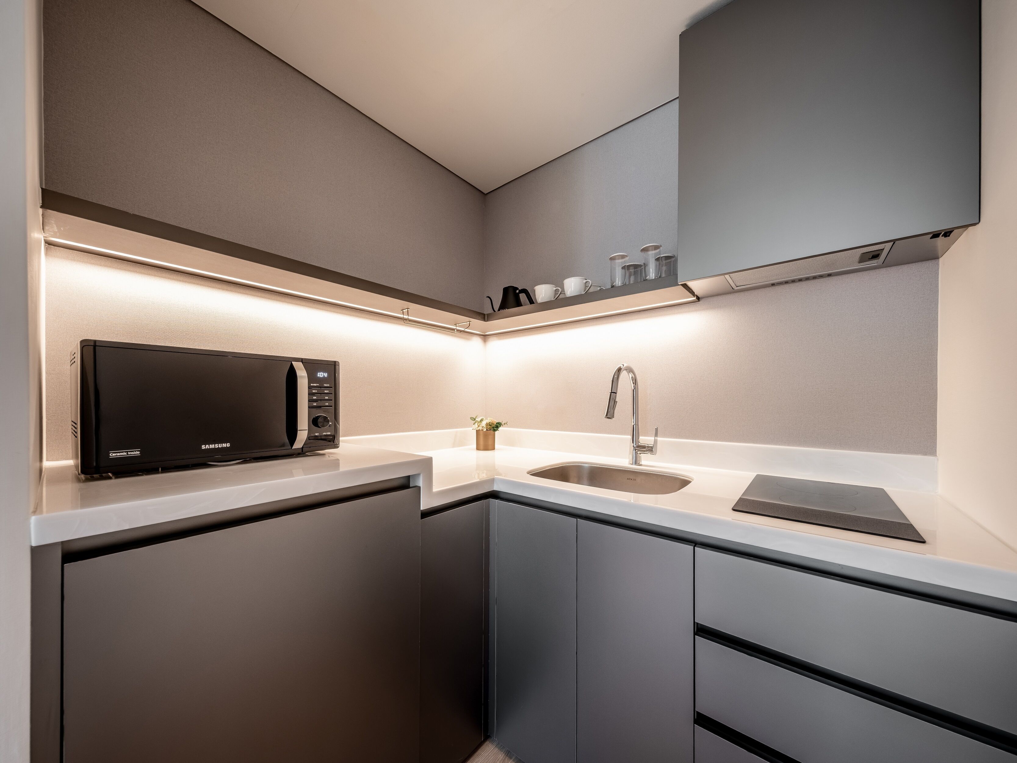 A modern kitchen with a built-in microwave, stainless steel sink, and sleek cabinetry.