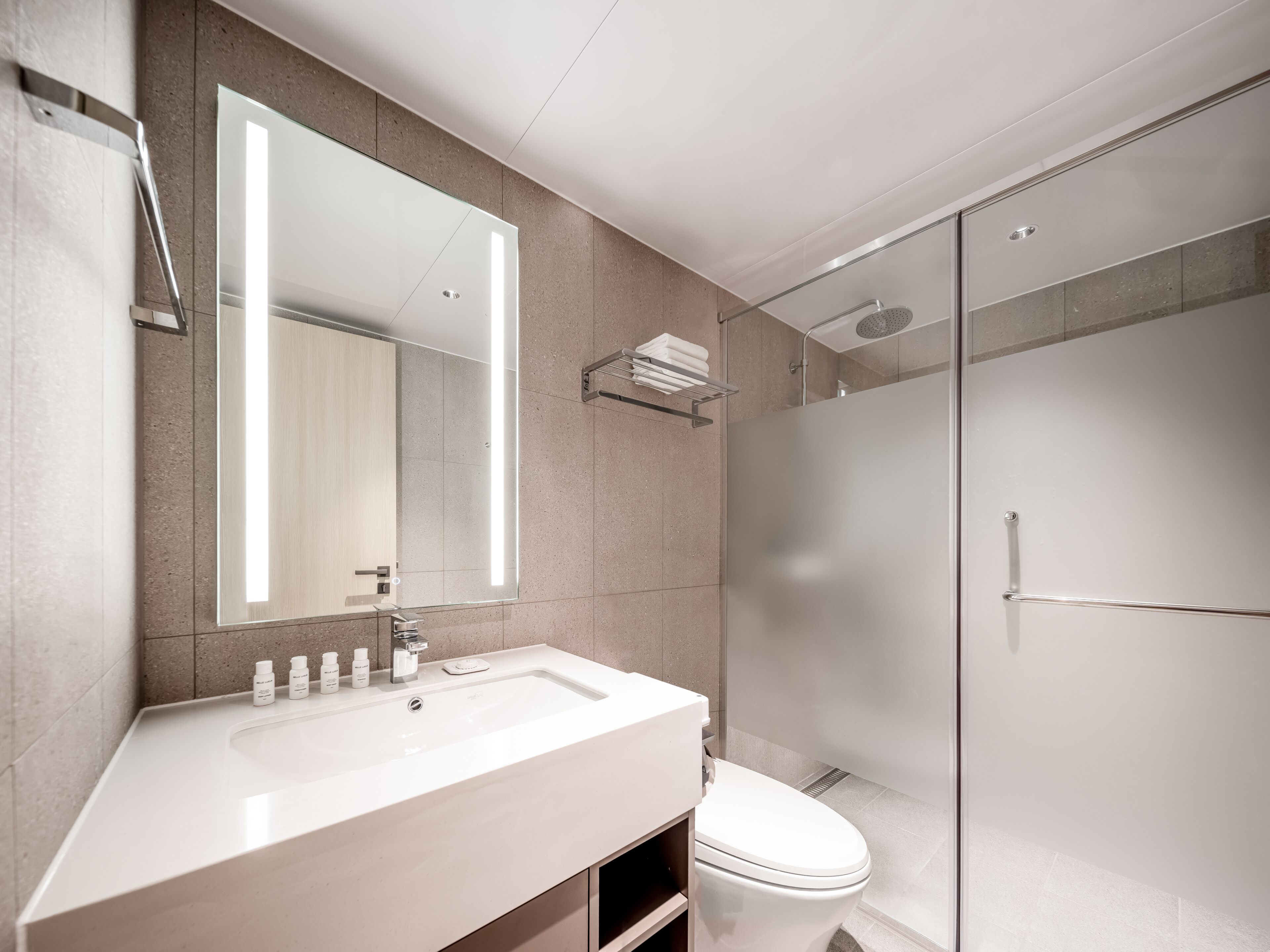 A modern bathroom with a large mirror, a white sink, and a glass-enclosed shower.