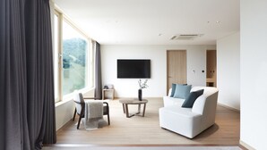 Een moderne woonkamer met een witte bank, een klein rond tafeltje en een aan de muur bevestigde televisie.