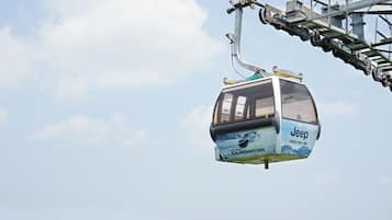 A cable car with a Jeep advertisement, suspended by a cable system.