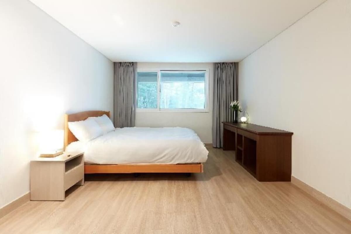 Une chambre à coucher avec un lit, une table de chevet et un bureau avec une lampe.