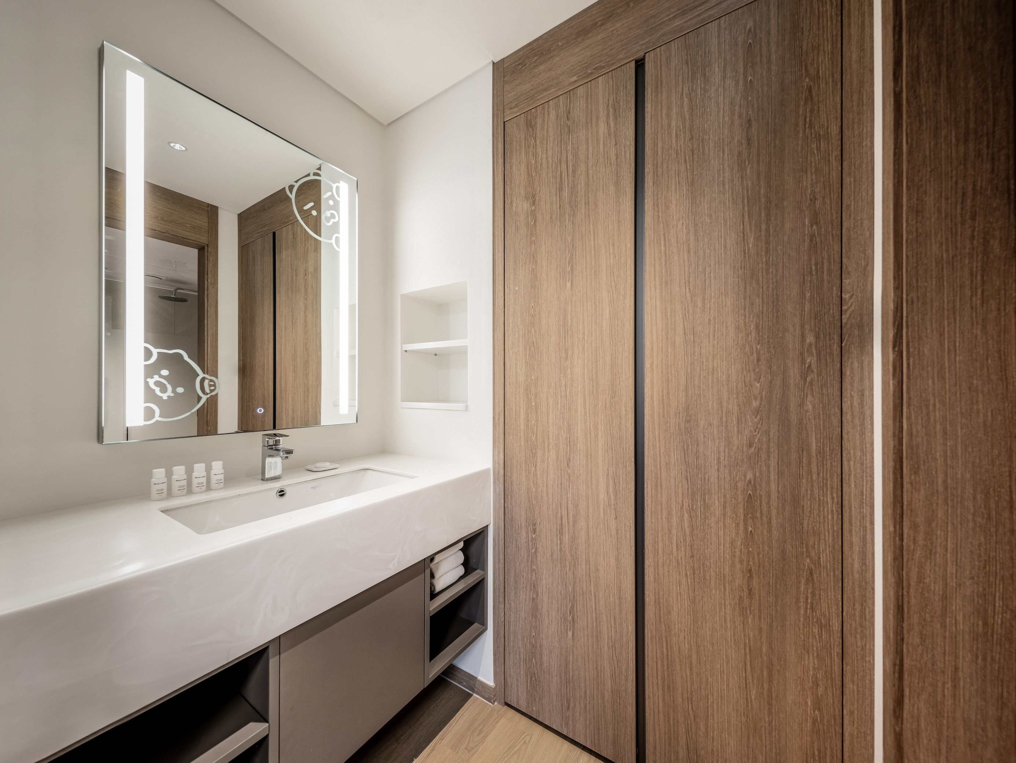 Un bagno moderno con uno specchio grande, un lavandino bianco e mobili in legno.