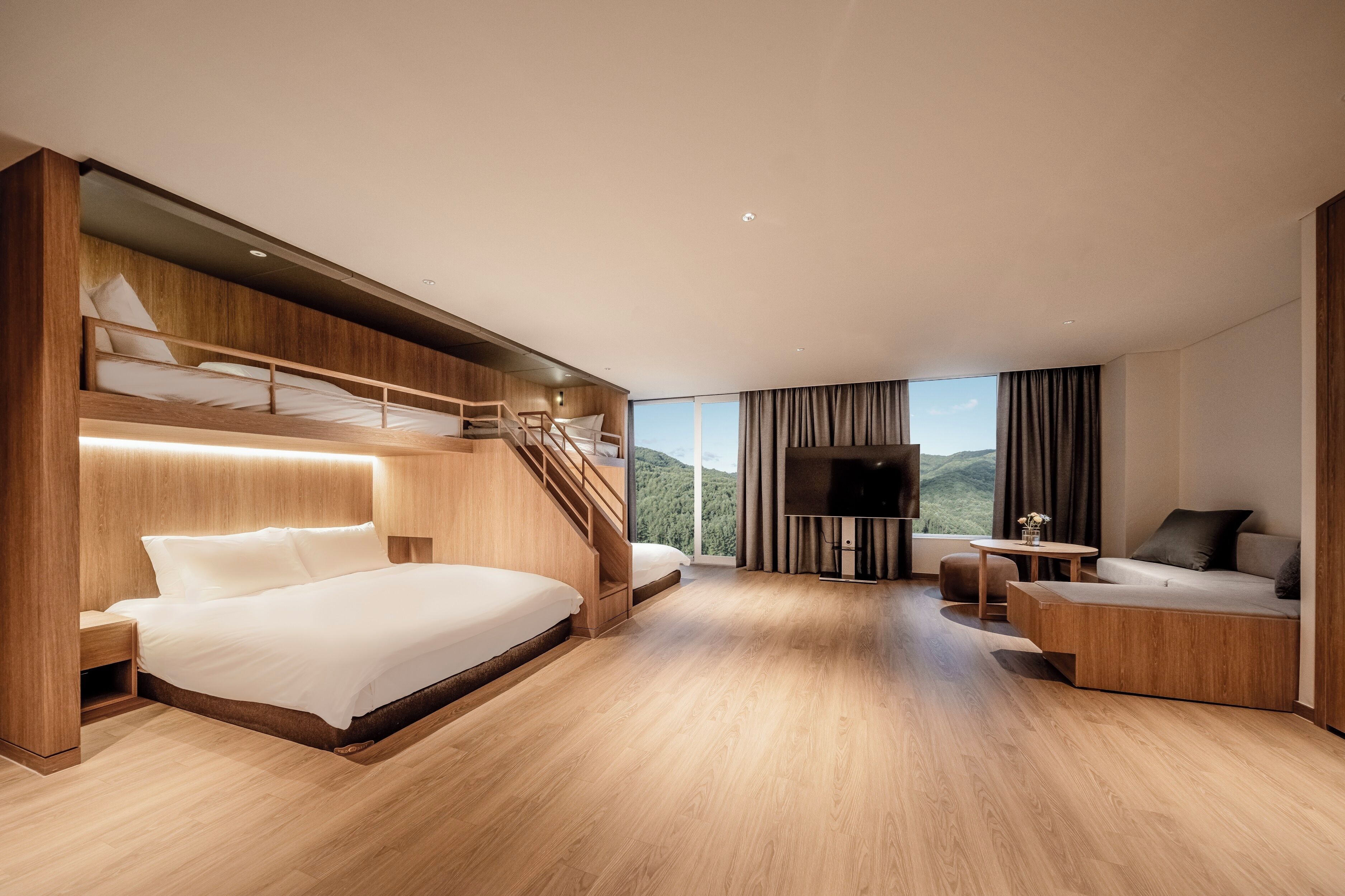 Une chambre d’hôtel moderne dotée d’un grand lit, d’un canapé, d’une télévision et d’un escalier menant à un niveau supérieur.