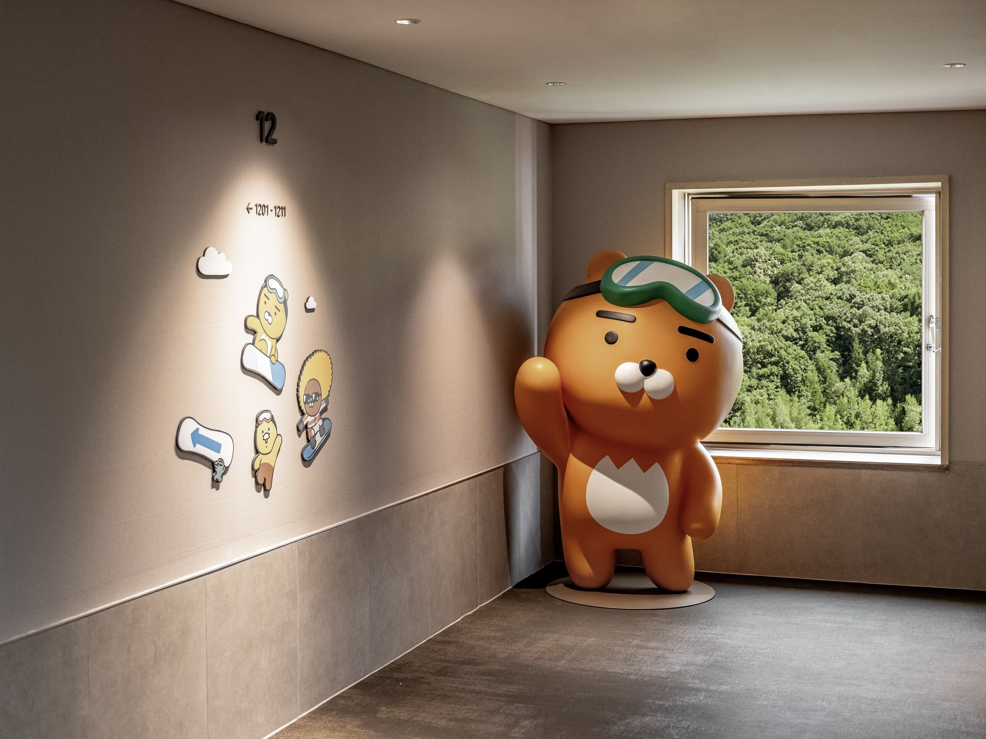Una estatua de oso en una habitación con un ventanal grande, una pared con flechas direccionales y el número '12' en la pared.
