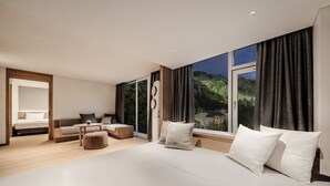 Een moderne slaapkamer met een groot bed, een bank, een kleine tafel en uitzicht op groen.