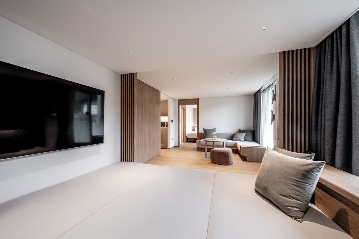 Ein modernes Wohnzimmer mit großem Flachbildfernseher, einer Couch, einem Couchtisch und einem Essbereich mit Stühlen.